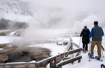 Two people snowshoeing on a boardwalk